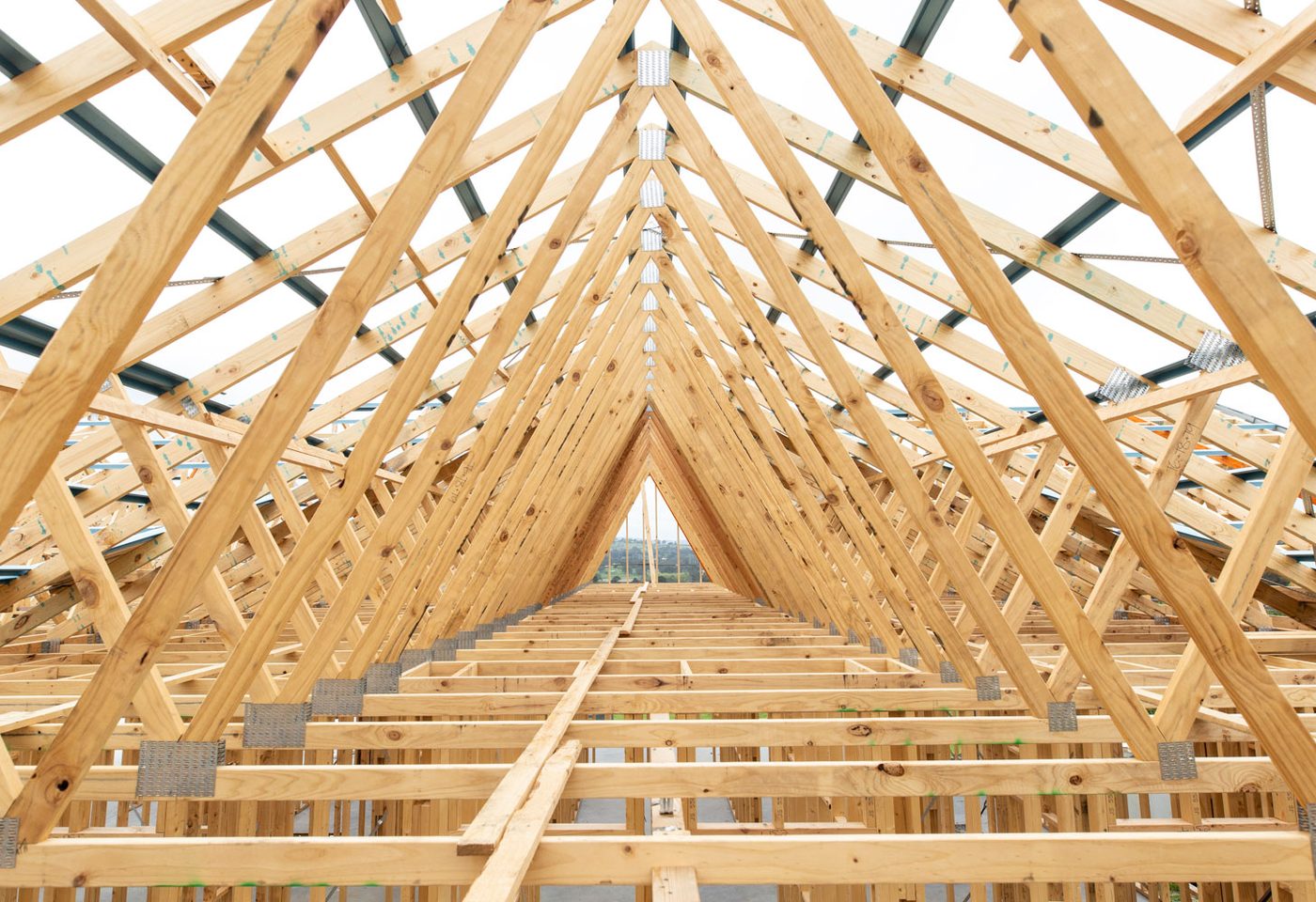 Enfilade de fermettes en bois vue de l'intérieur d'une toiture en cours de montage